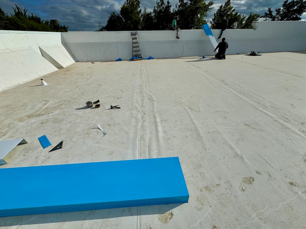 Roofers performing an installation on a sloped roof with professional equipment